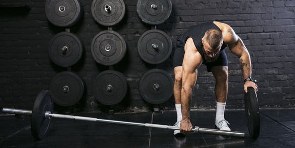 Man changing bumper plates on a barbell