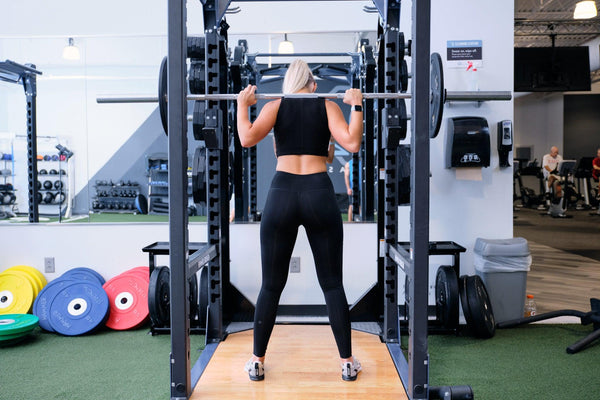 Young woman using a squat rack 